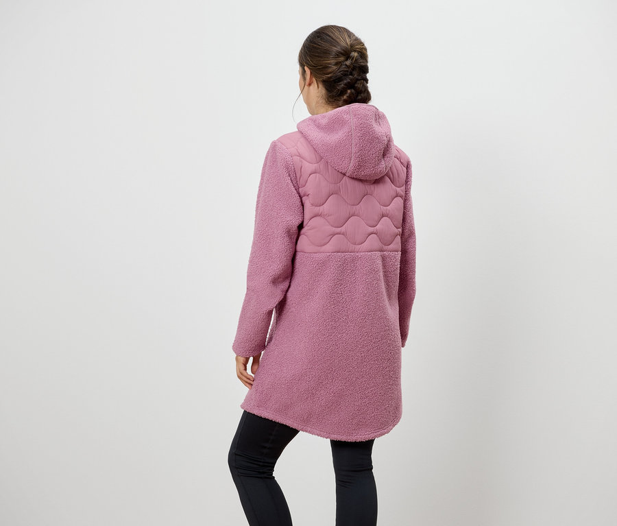 Hátulról látható nő rózsaszín kapucnis kabátot és fekete leggingset visel.
