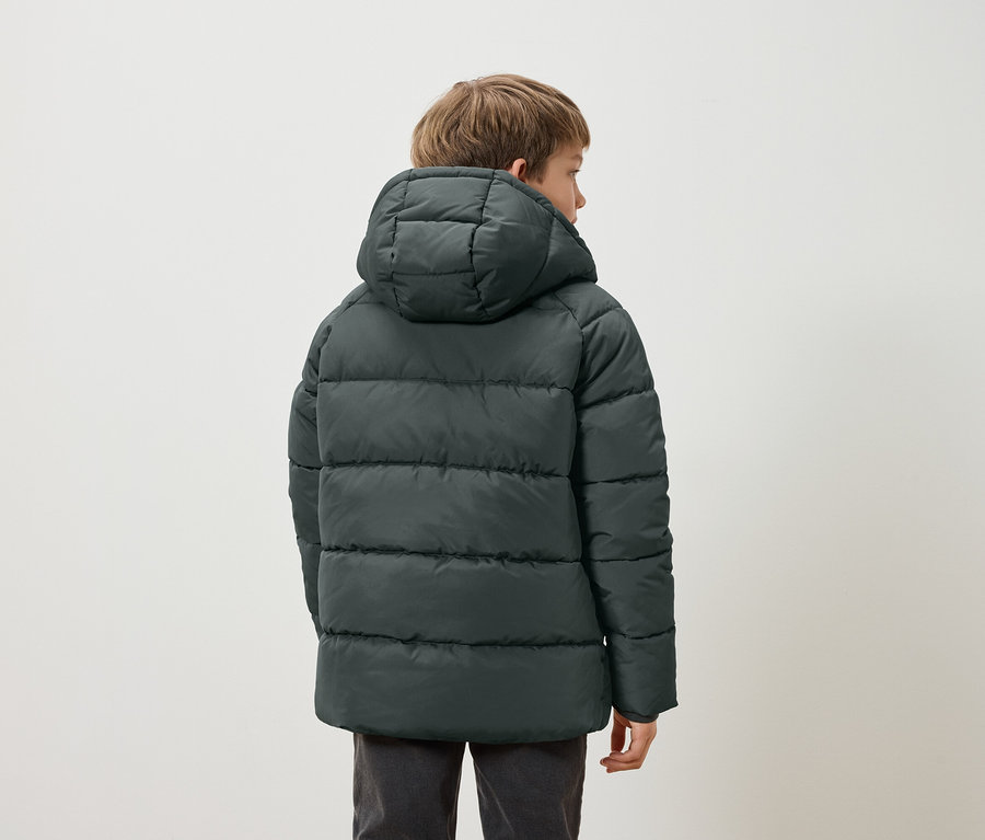 Hátulról látható fiú sötétzöld, kapucnis, steppelt kabátban.