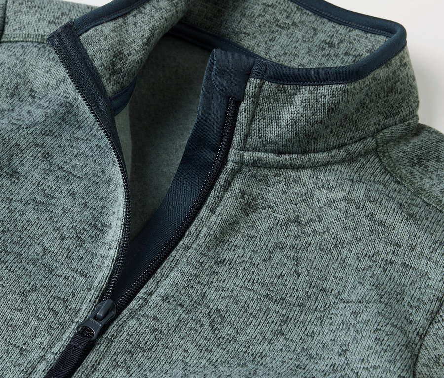 Egy gyerek hibrid kötött polárfelső részlete nyitott cipzárral.