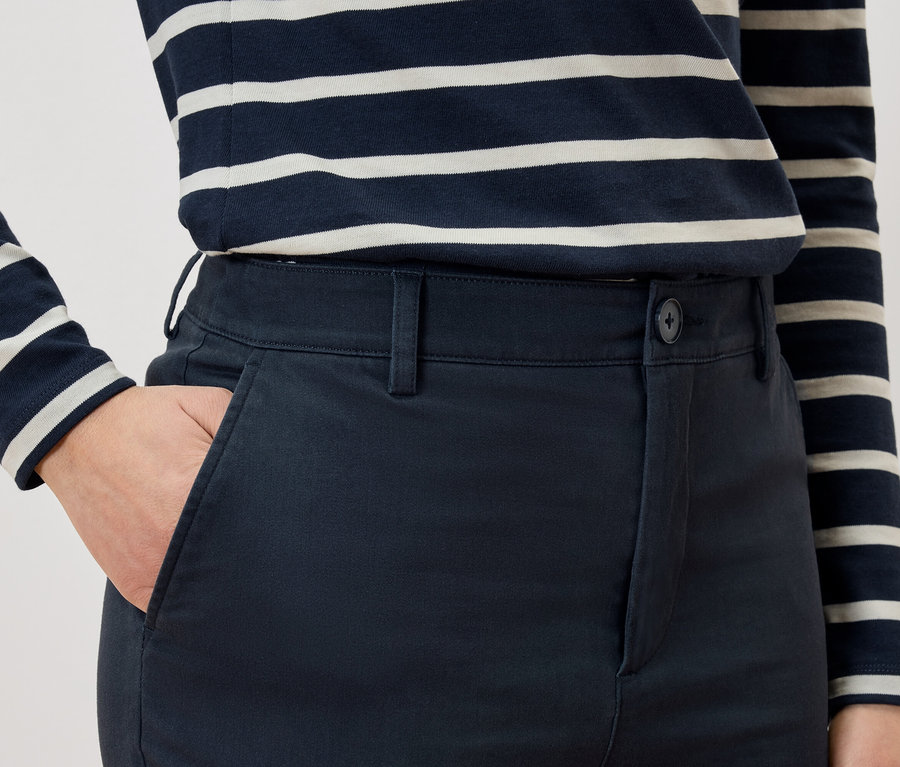 Egy személy részlete, amint a keze a nadrágzsebében van, és egy csíkos pólót visel.