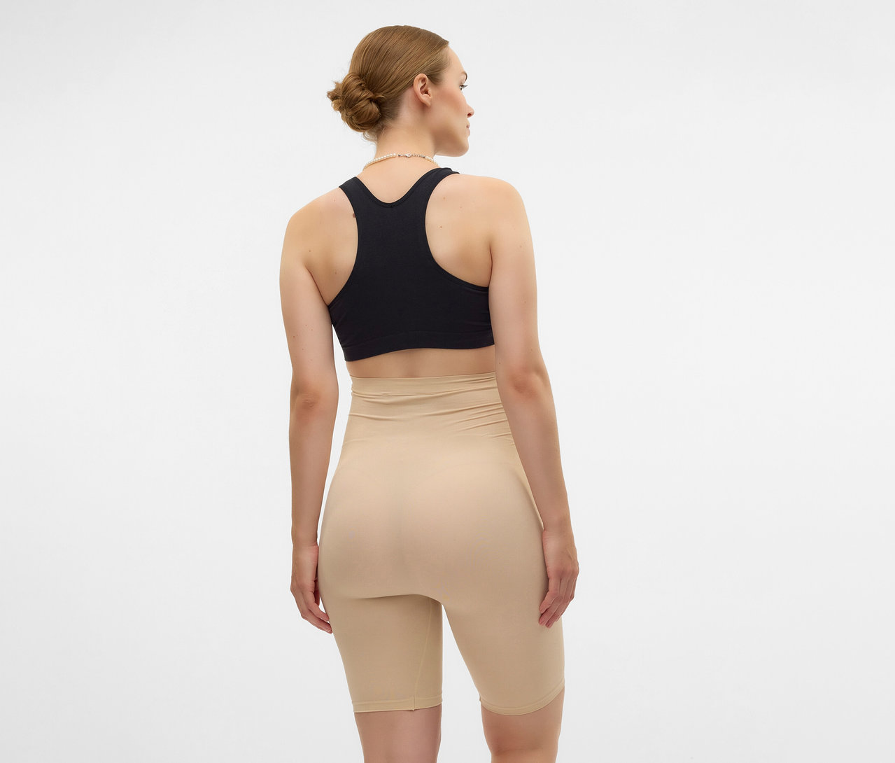 Hátulról látható nő fekete sportmelltartóban és bézs színű MAMALICIOUS kismama rövidnadrágban.