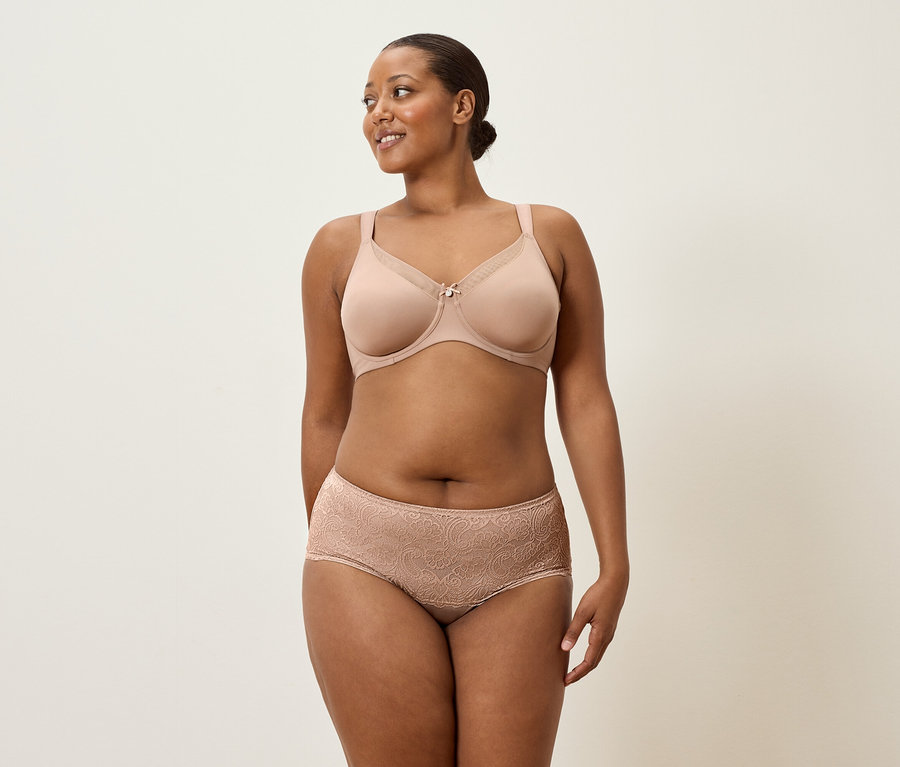 Nő visel testszínű melltartót és csipkés alsóneműt.