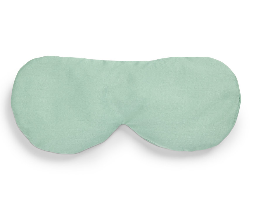 Egy világoszöld alvómaszk fekszik egy fehér háttéren.