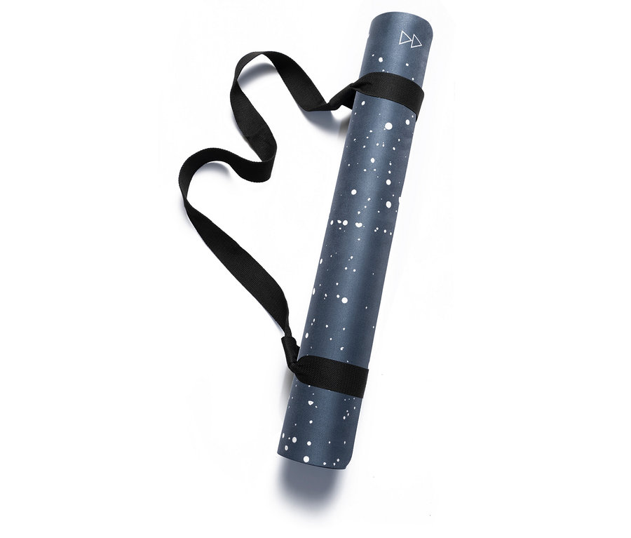 Egy feltekert kék jógamatrac fehér pöttyökkel és fekete hordozópánttal.