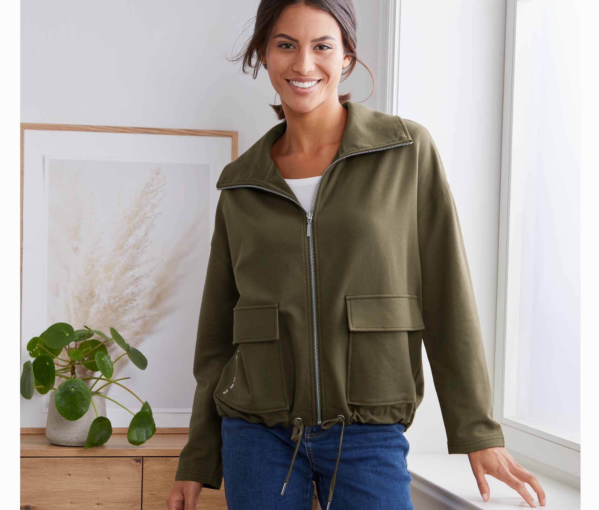 Nő visel egy khaki színű női szabadidőfelsőt.