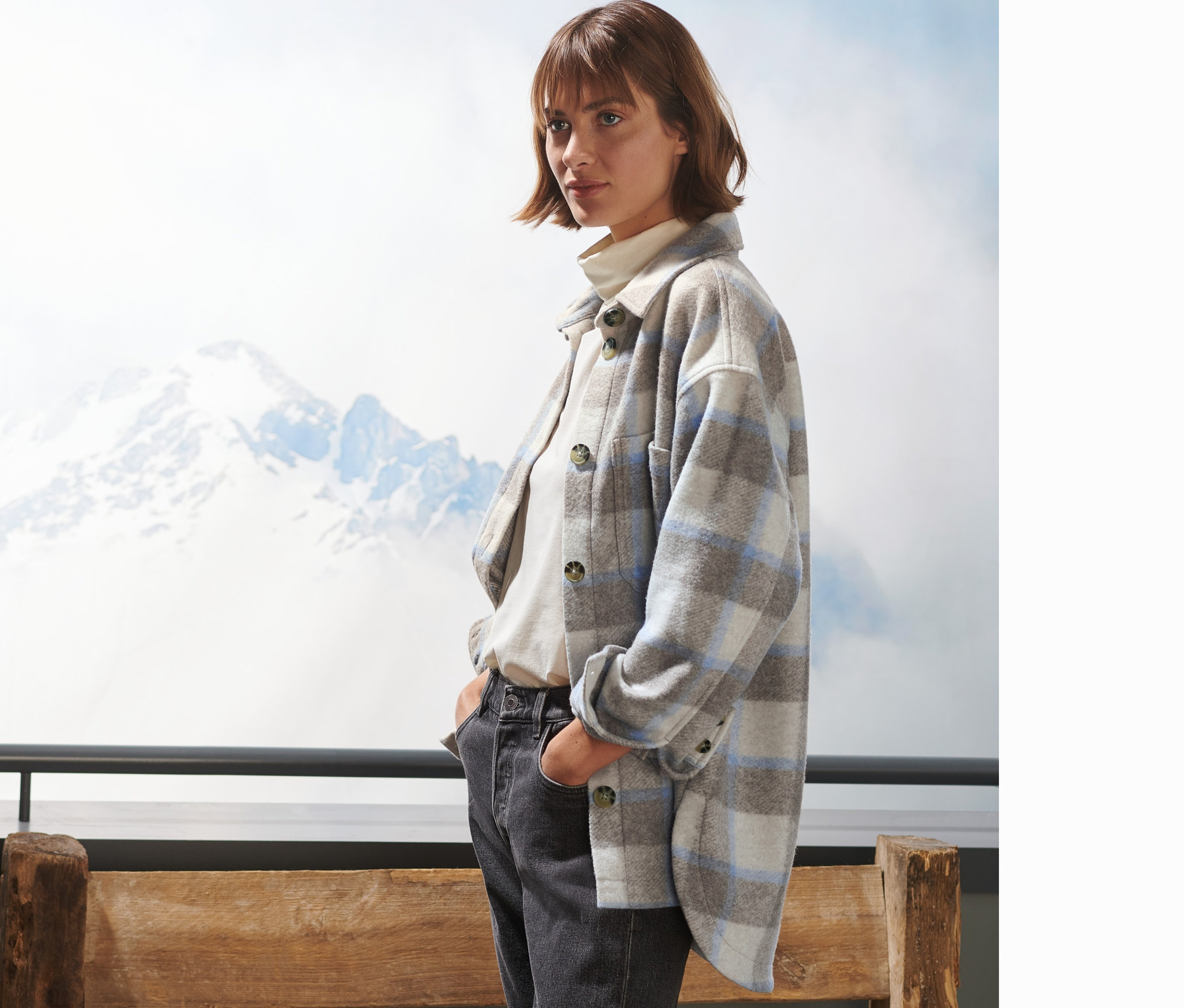 Nő kockás ingkabátot és farmert visel.