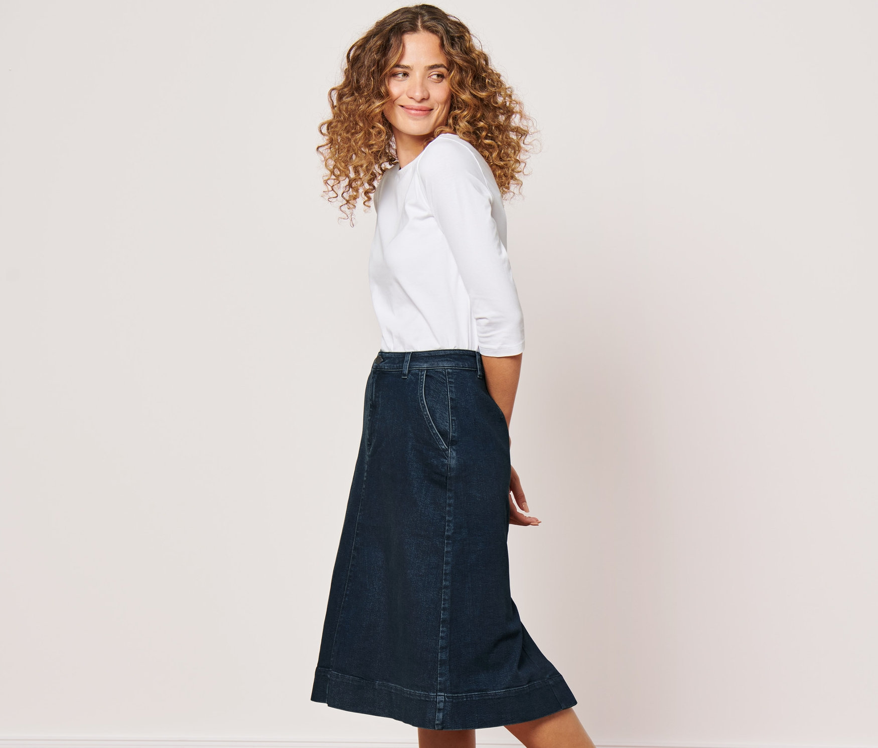 Nő pózol női midi farmerszoknyában.