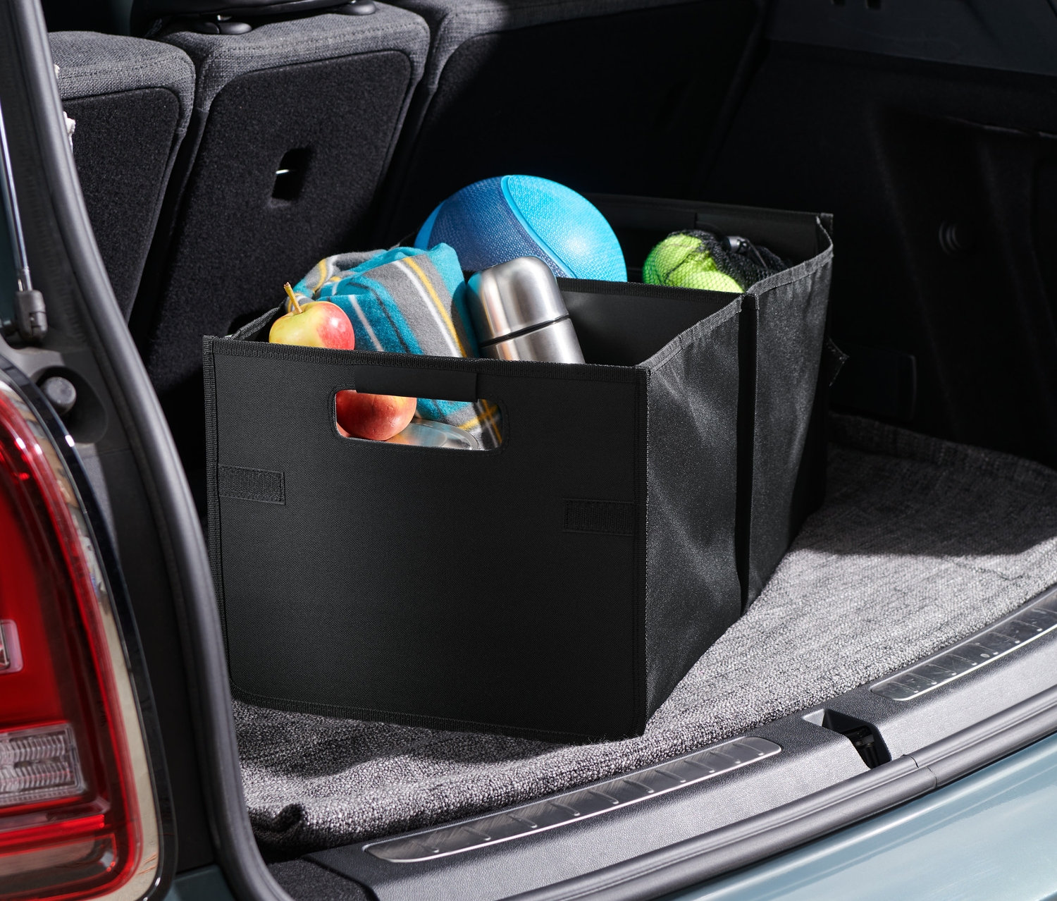 Egy autó csomagtartójában egy összehajtható doboz autóba található, benne különféle tárgyakkal.