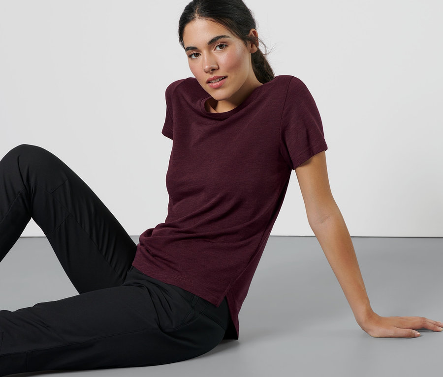 Nő ül a padlón, melírozott padlizsán színű sportfelsőben.