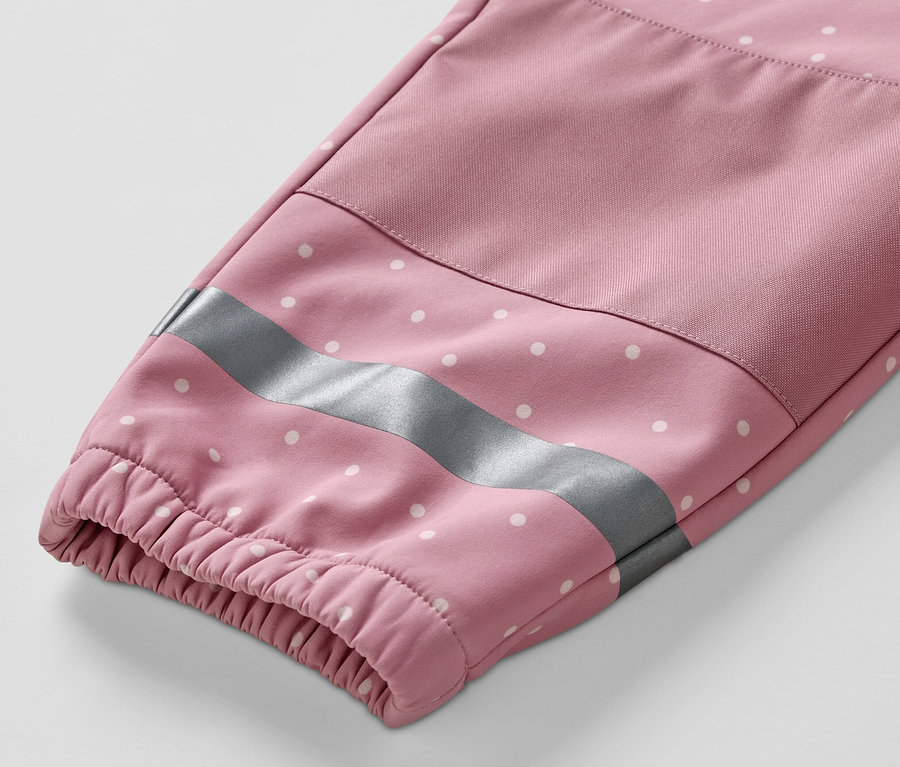 Egy gyermek softshell kezeslábas ujjának részlete fehér pöttyökkel és fényvisszaverő csíkkal.