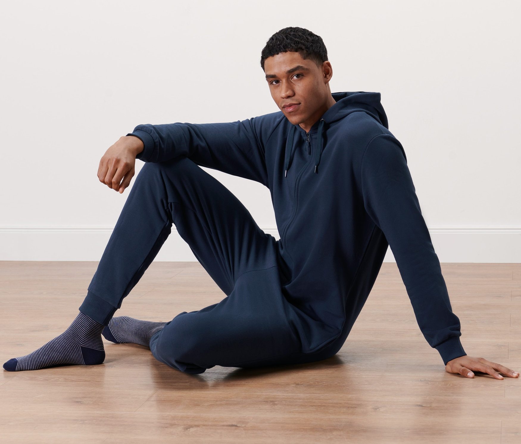 Férfi ül a padlón sötétkék férfi kezeslábasban.