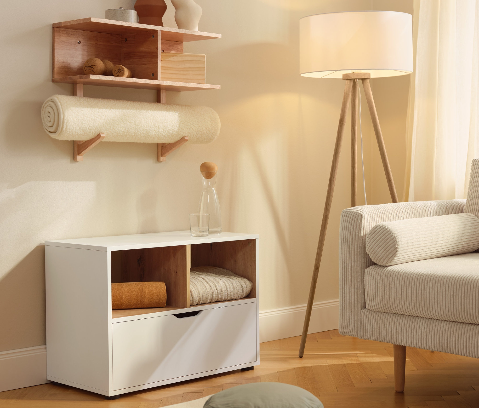 Komód fiókkal a nyírt gyapjú jógamatrac mellett. A falon egy fali polc látható.