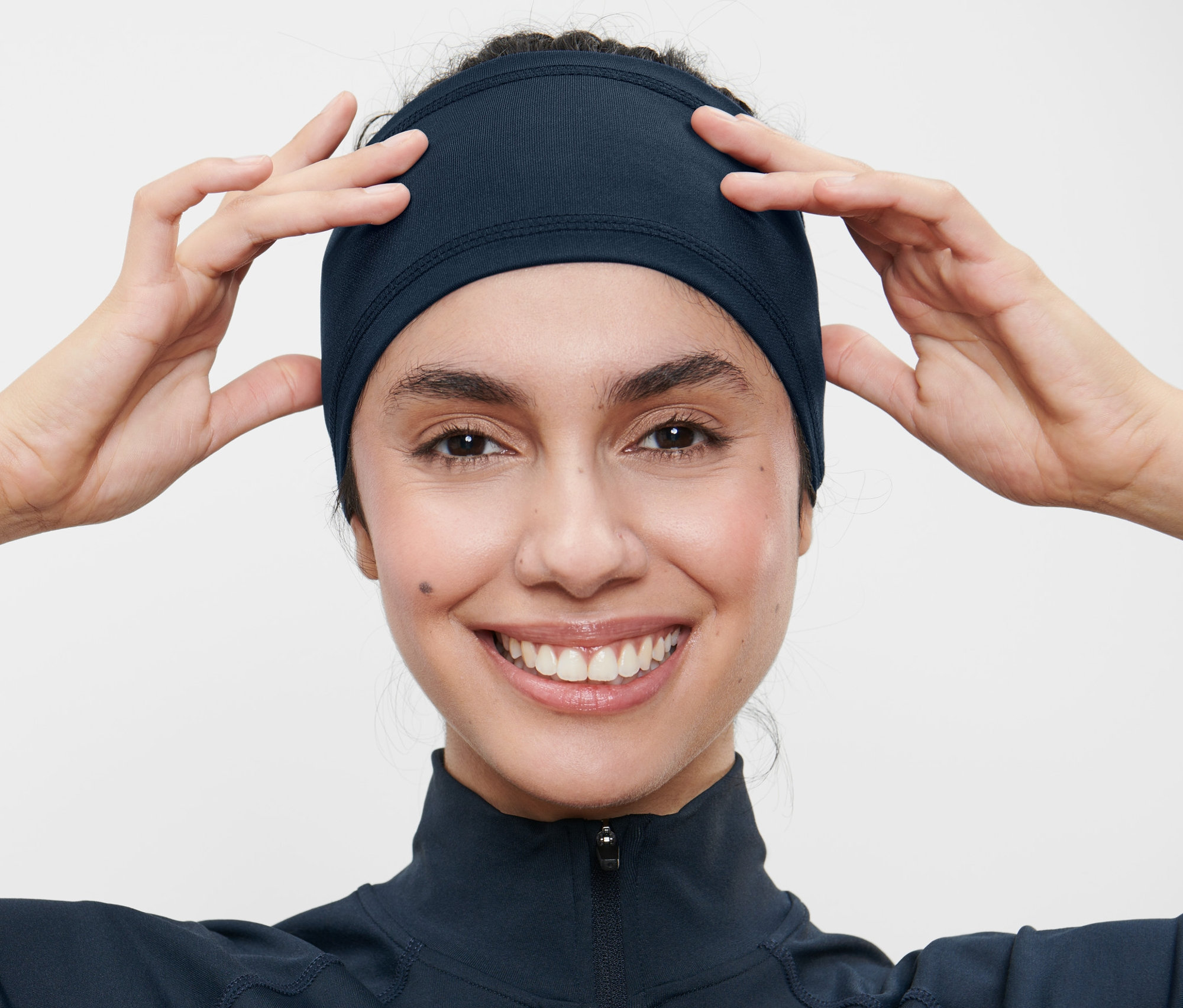 Nő igazítja a sötétkék sportfejpántot.