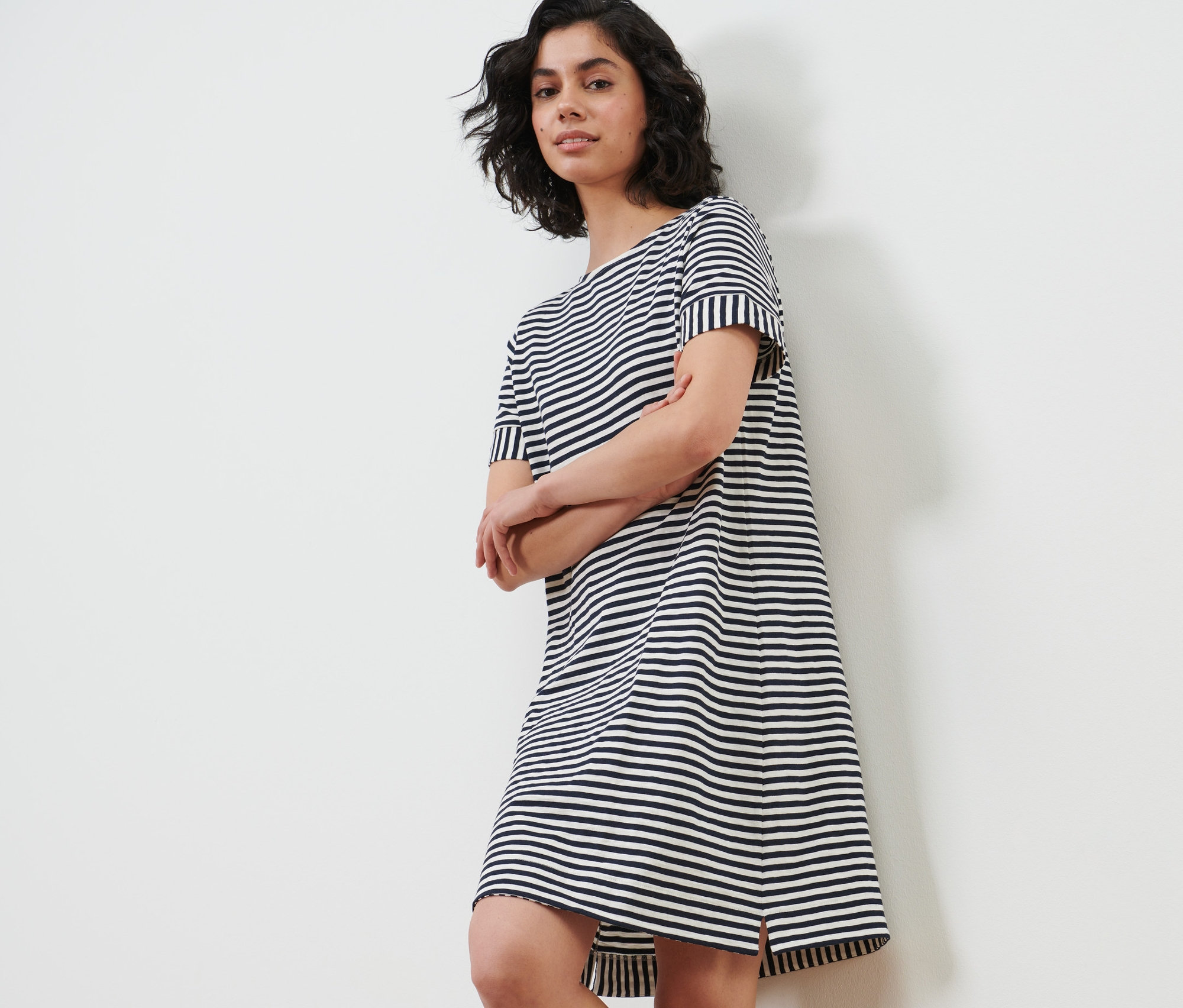 Nő pózol egy csíkos jersey ruhában.