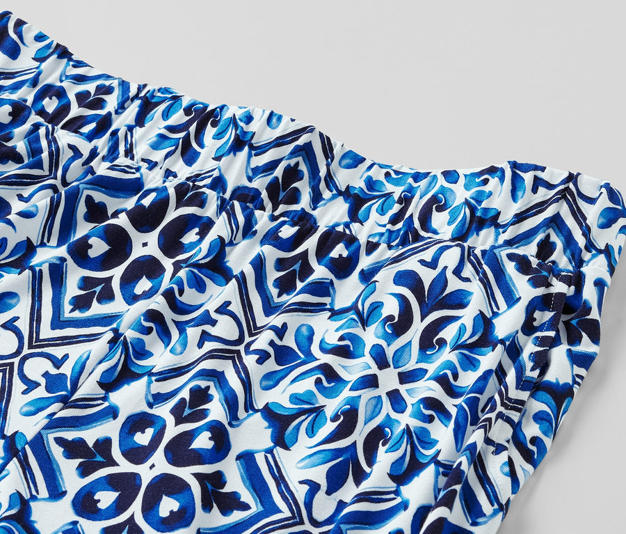 Kék, mintás, bő szárú nadrág részlete gumis derékrésszel.