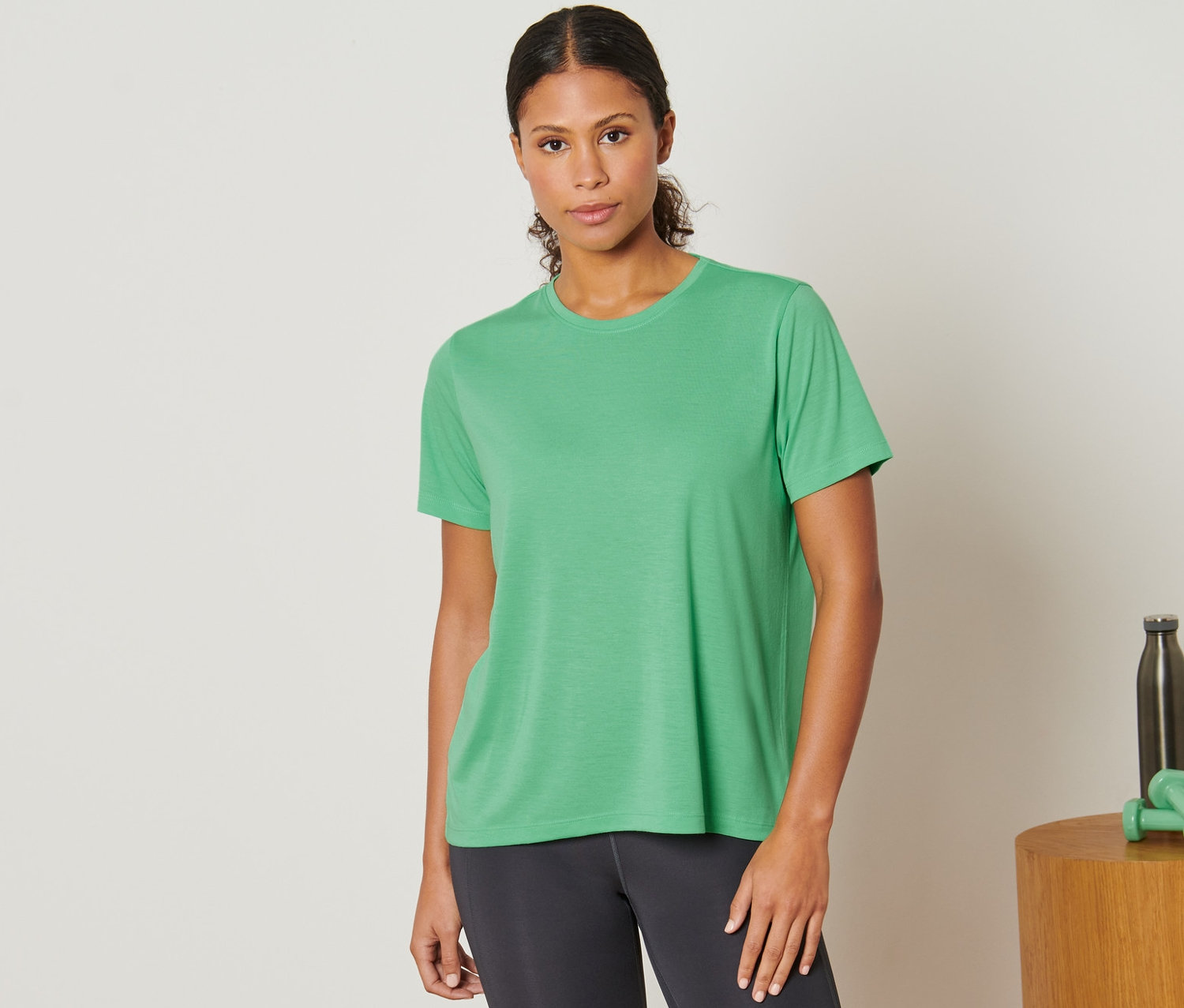 Nő visel világoszöld sportfelsőt.