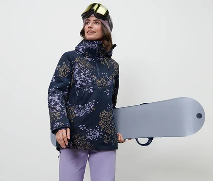 Nő snowboardot tart és női félcipzáras síkabátot visel.