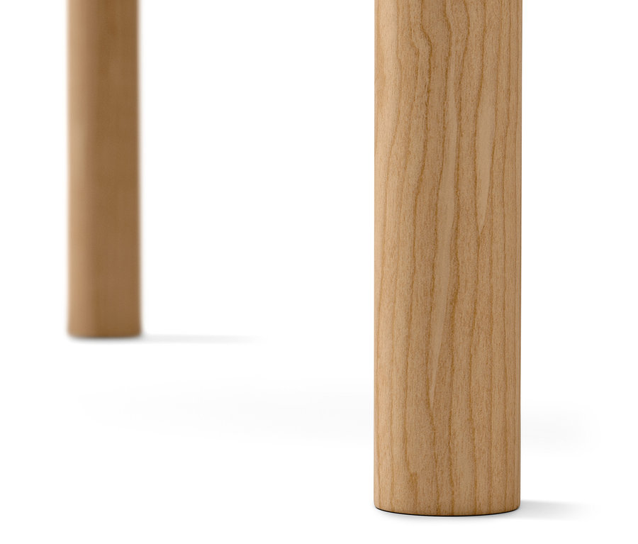 Egy világos fa asztal két lábának részlete fehér háttérrel.