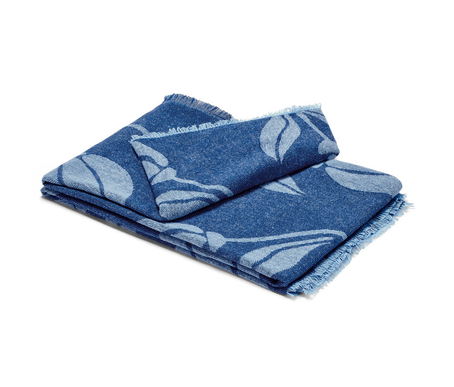 Összehajtott, virágos, kék takaró rojtokkal.