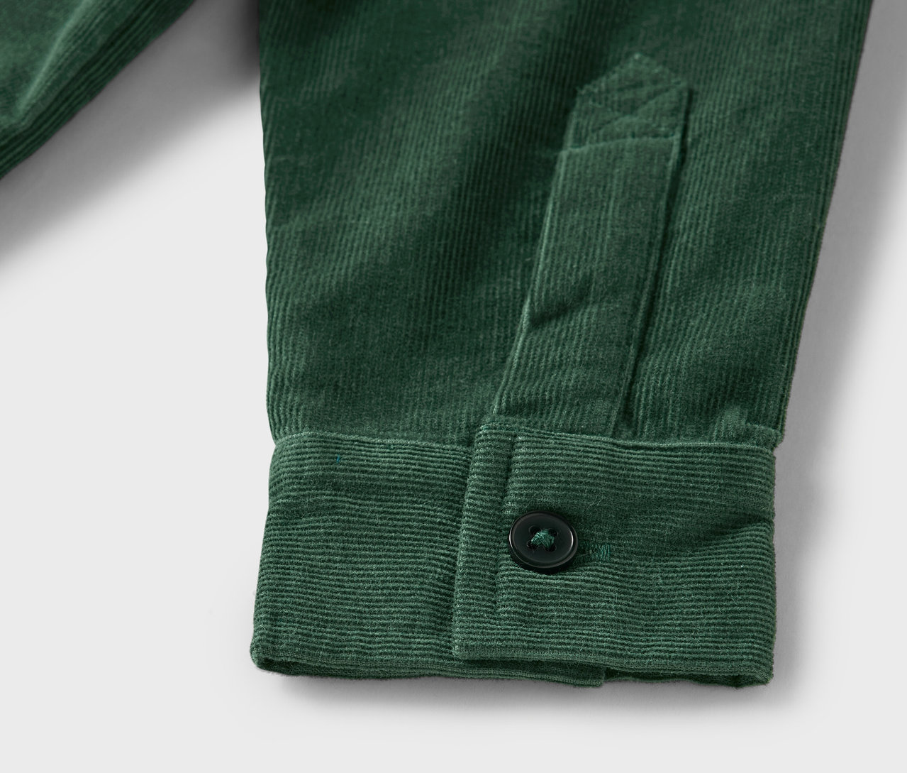 Egy zöld kordbársony ing részlete, gombbal a mandzsettán.