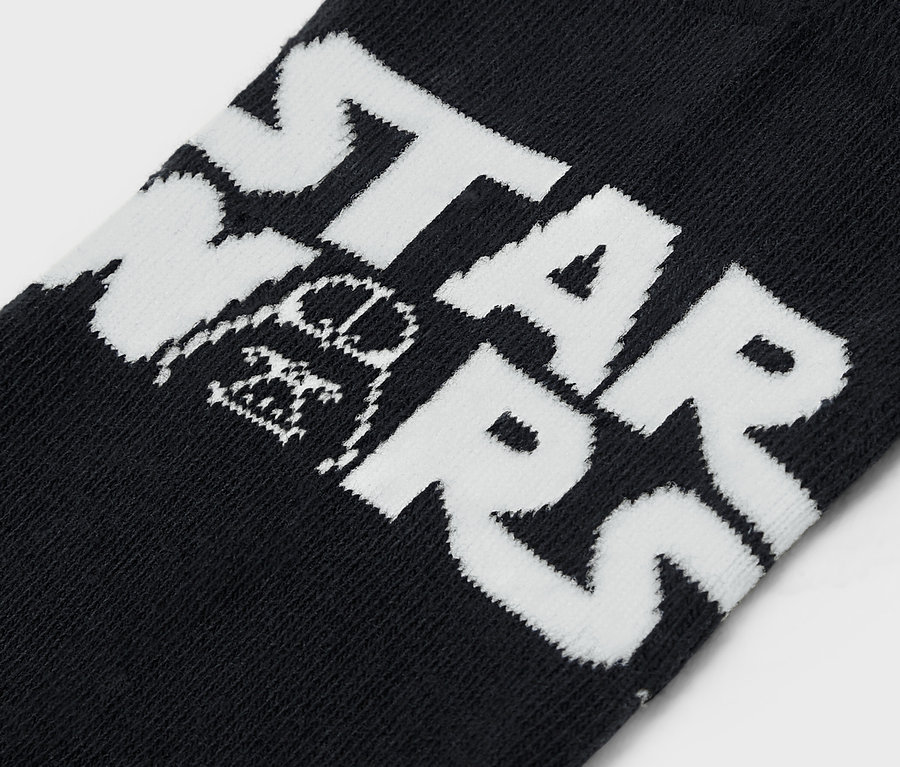 Egy fekete zokni részlete fehér STAR WARS felirattal és Darth Vader ábrázolásával.