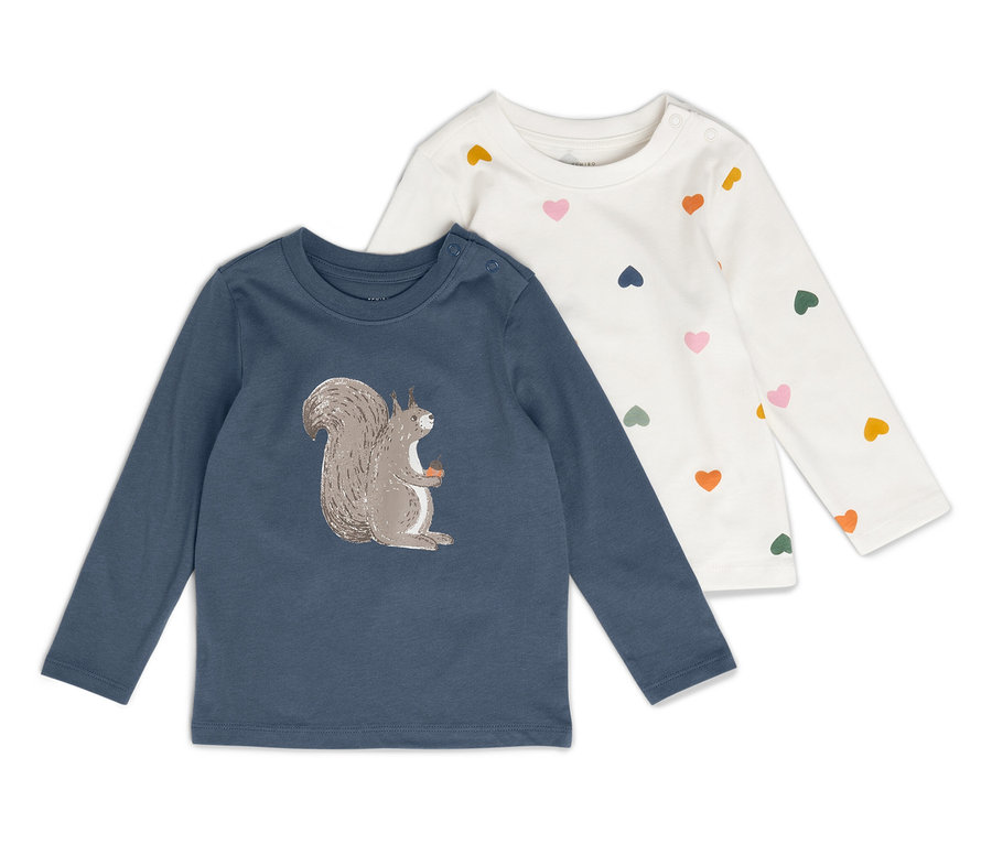 Két gyermek hosszú ujjú póló fekszik egymás mellett. Az egyik póló kék, mókus képpel, a másik fehér, színes szívekkel.