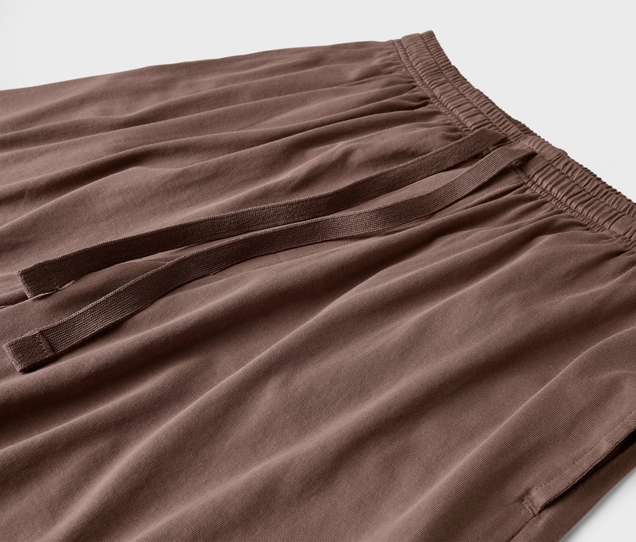 Egy barna színű nadrág közeli képe, húzózsinórral és zsebekkel.