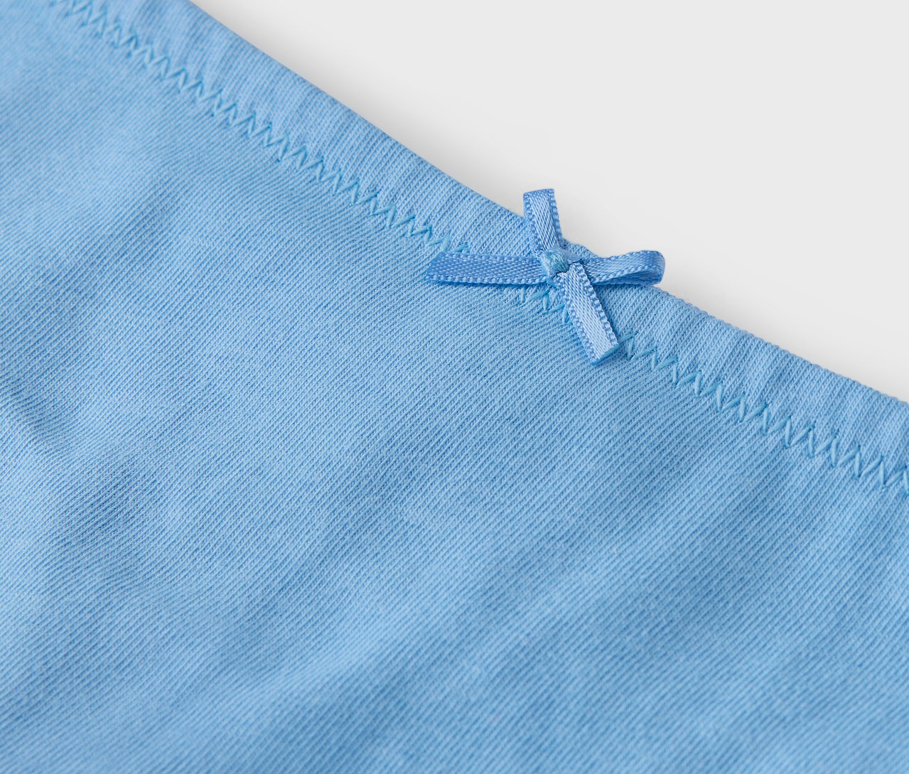 Egy világoskék bugyi részlete masnival.