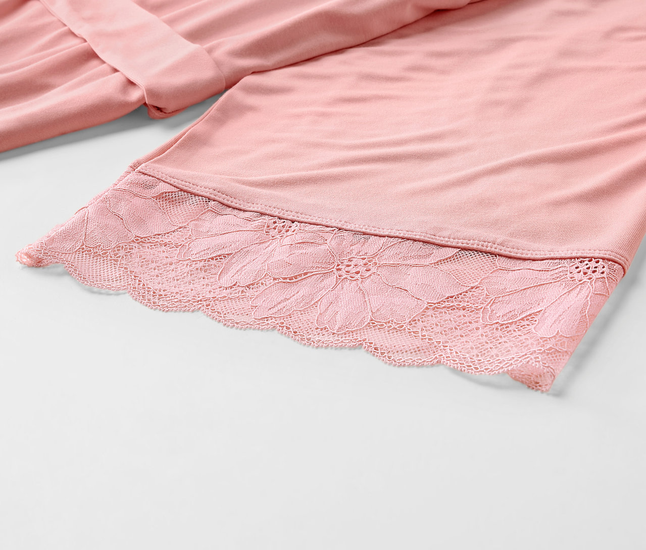 Rózsaszín köntös részlete csipkével.