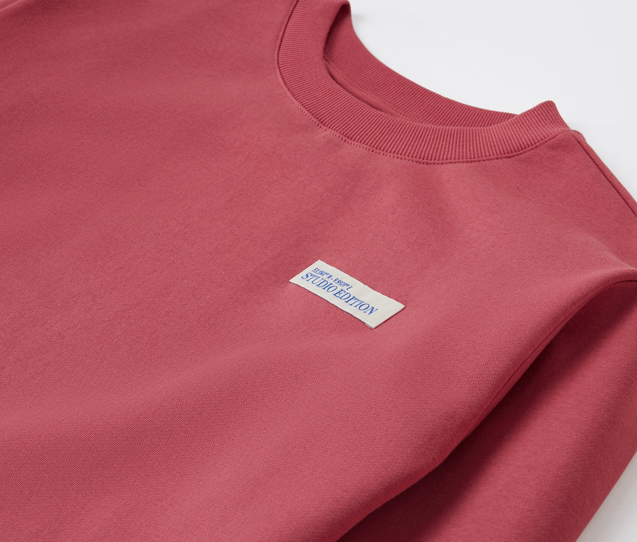 Egy piros gyerek szabadidőfelső részletgazdag képe, Studio Edition felvarróval.