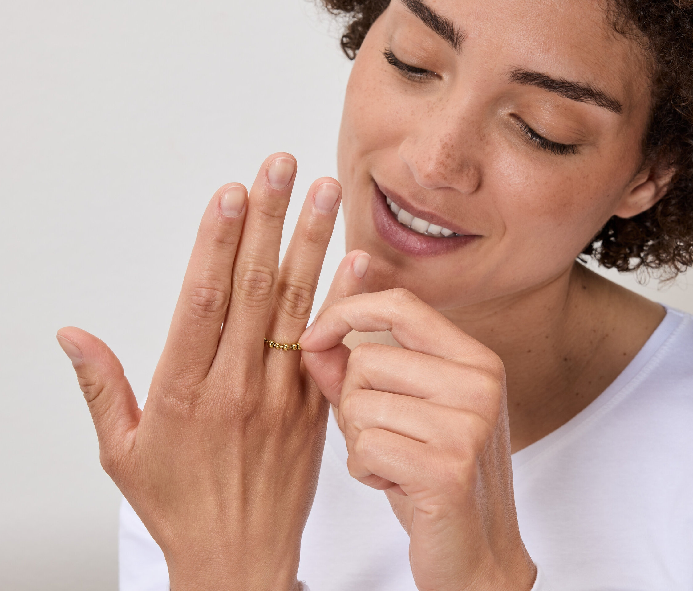 Nő nézeget egy arany gyűrűt az ujján.