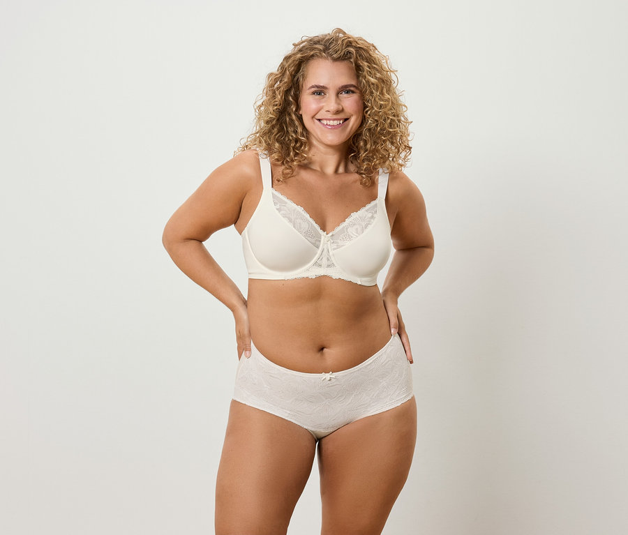 Göndör hajú nő fehérneműben pózol.