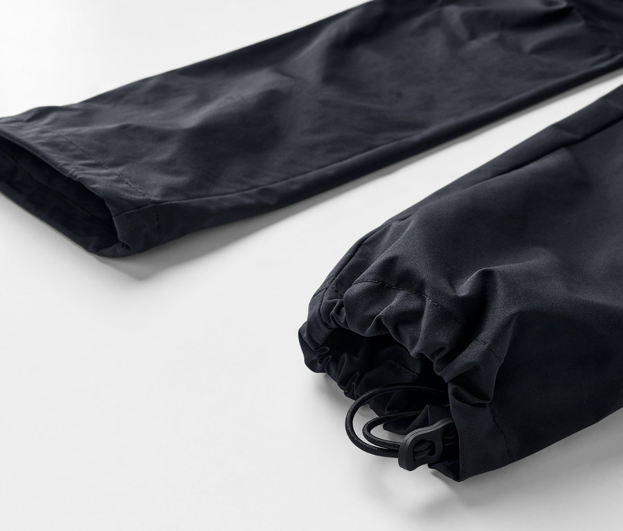 Egy fekete, 2 az 1-ben funkcionális nadrág részletfotója, húzózsinórral a szár alján.