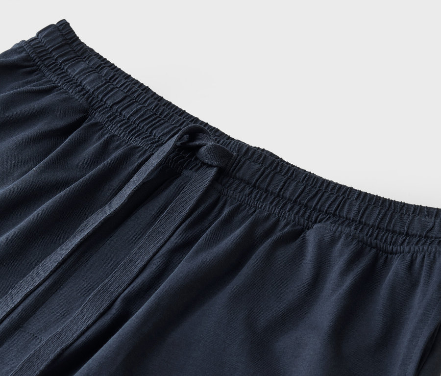 Közeli kép egy sötétkék szövetnadrágról húzózsinórral.