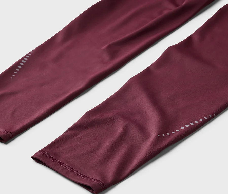 Bordó leggings közeli képe, fényvisszaverő pontokkal a bokánál.