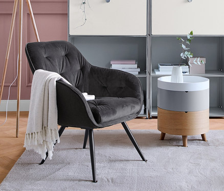 Nappali szürke polccal, fotellel és fa »háromlábú« állólámpával.