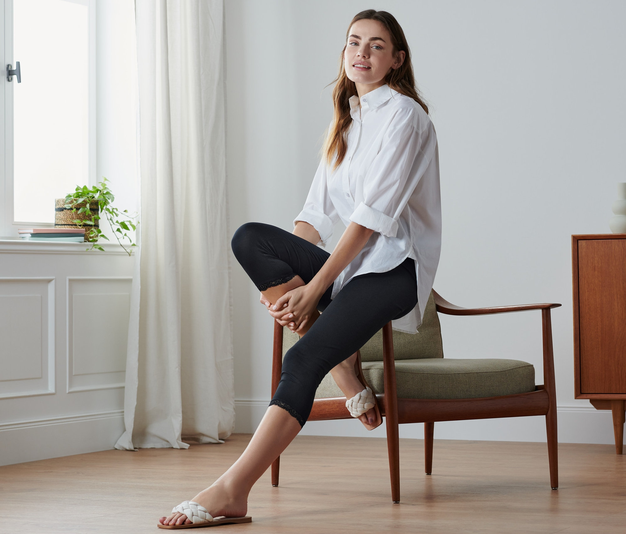 Nő ül a széken, fekete, csipkés 3/4-es leggingset visel.