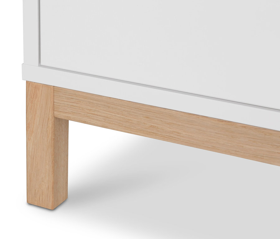 Egy fehér »Eklund« ruhásszekrény részlete fiókokkal és fa lábakkal.