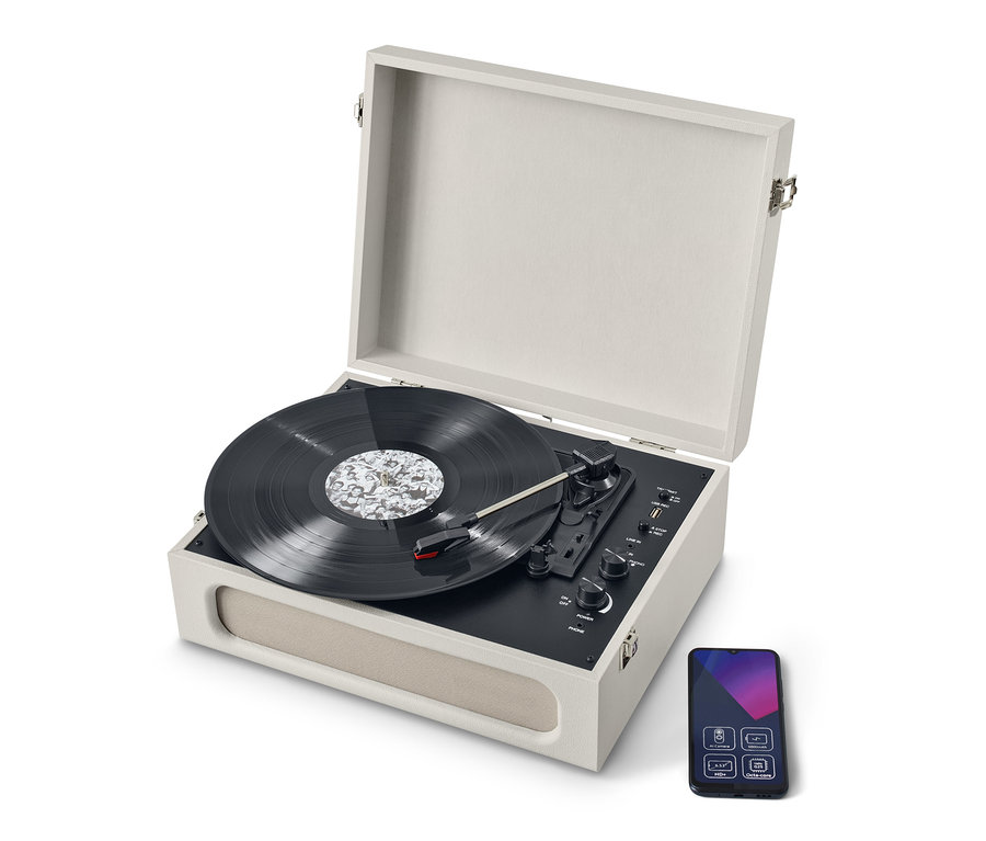 Egy bézs színű, hordozható retro lemezjátszó Bluetooth® funkcióval, nyitott fedéllel és egy lemezzel. A lemezjátszó mellett egy okostelefon található.