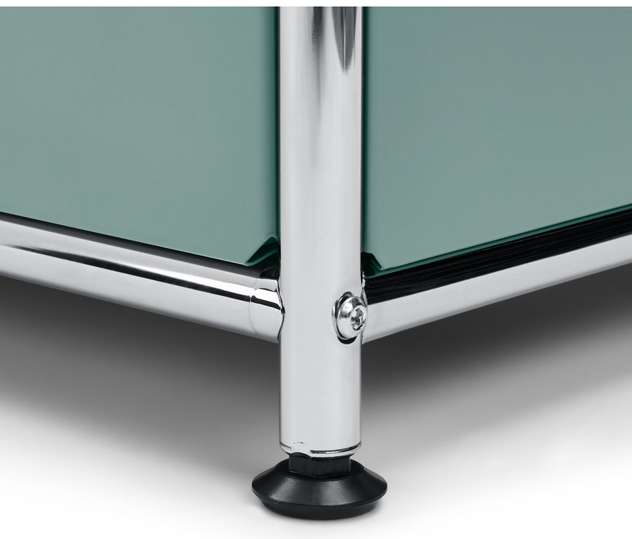 Közelkép egy zsályazöld színű »CN3« polcos komódról, 2 tetszőlegesen felszerelhető lenyíló ajtóval és krómozott lábakkal.