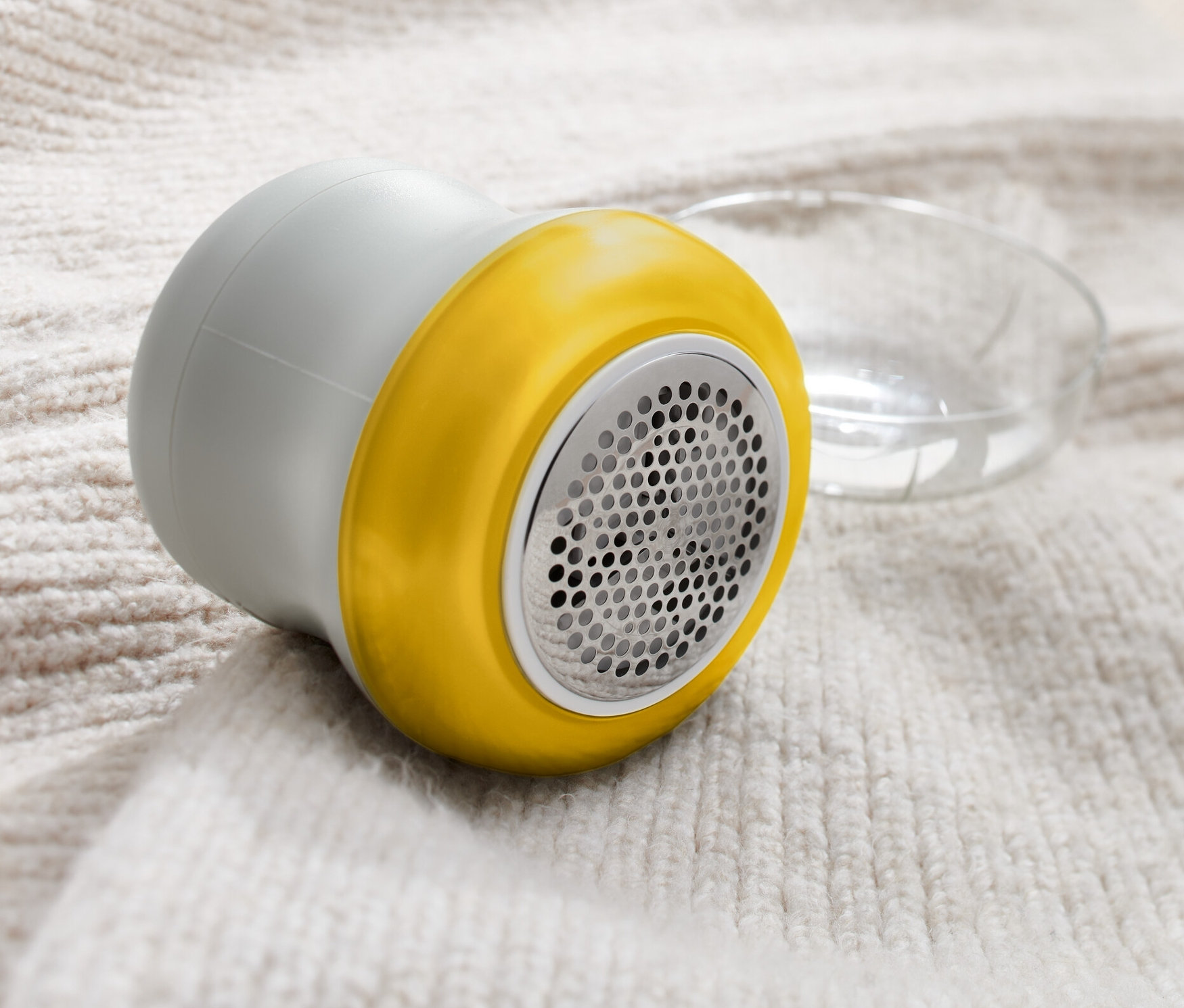 Egy szürke színű textilborotva fekszik egy világos gyapjúpulóveren.