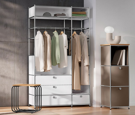 Belső tér fehér ajtóval, »CN3« fém komód 2 akasztórúddal és 4 fiókkal, »CN3« keskeny fém komód fa felső lappal, szürkésbarna, LED-es asztali dizájnlámpa és ülőke.