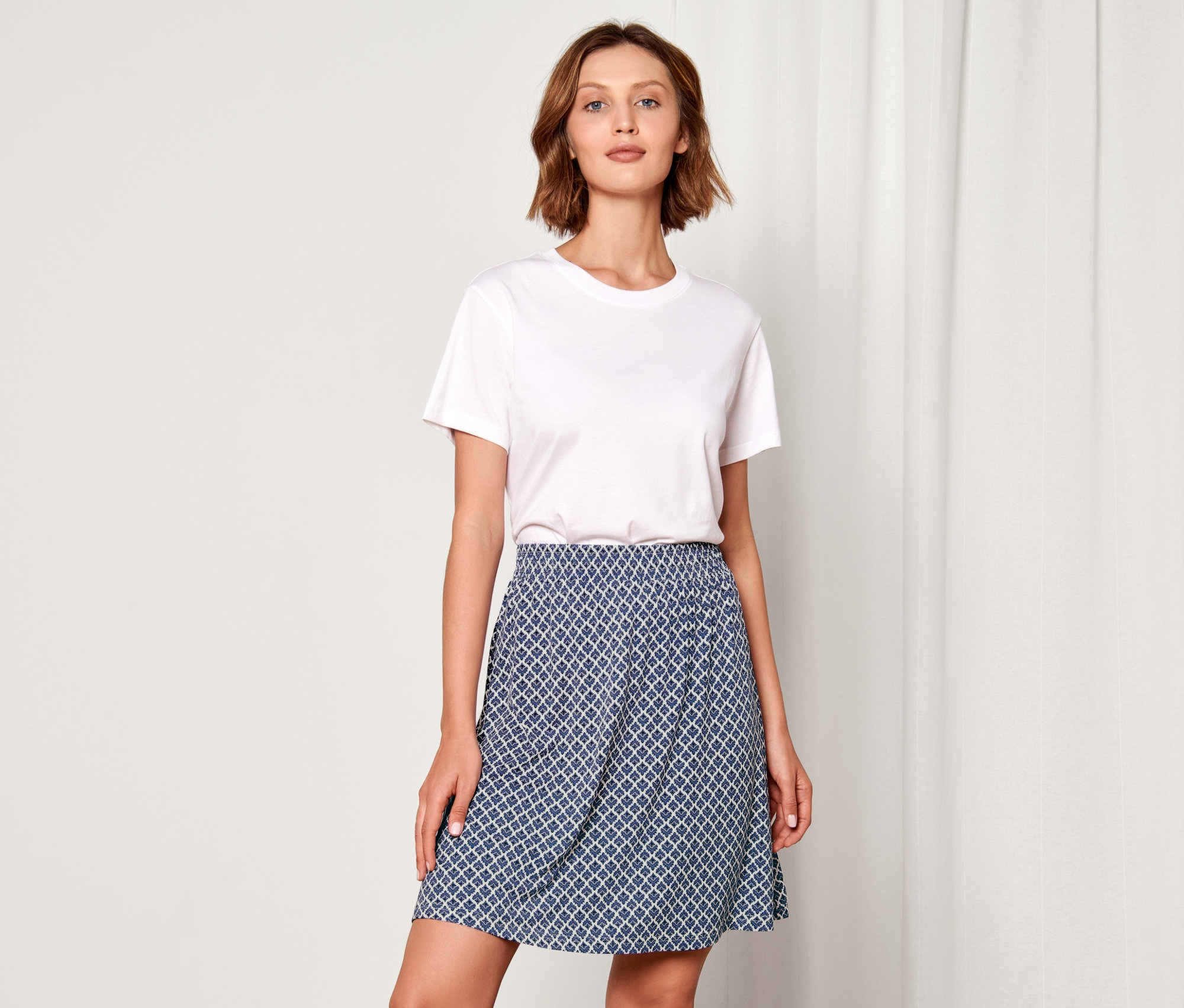 Nő pózol mintás dzsörzészoknyában.