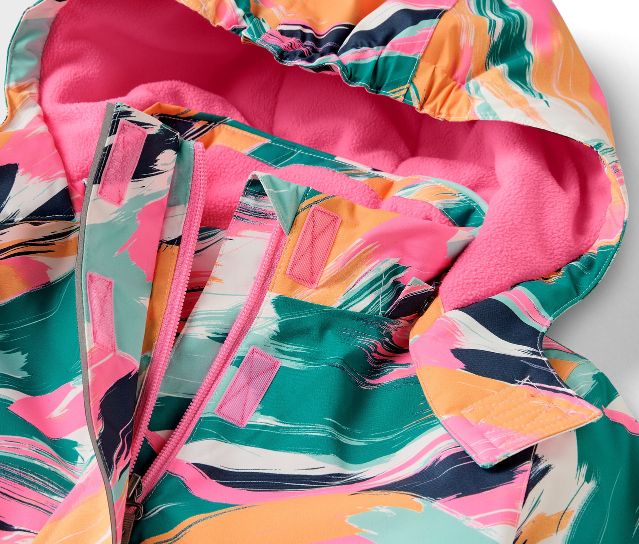 Egy színes mintás, rózsaszín bélésű kapucnis kabát részlete.