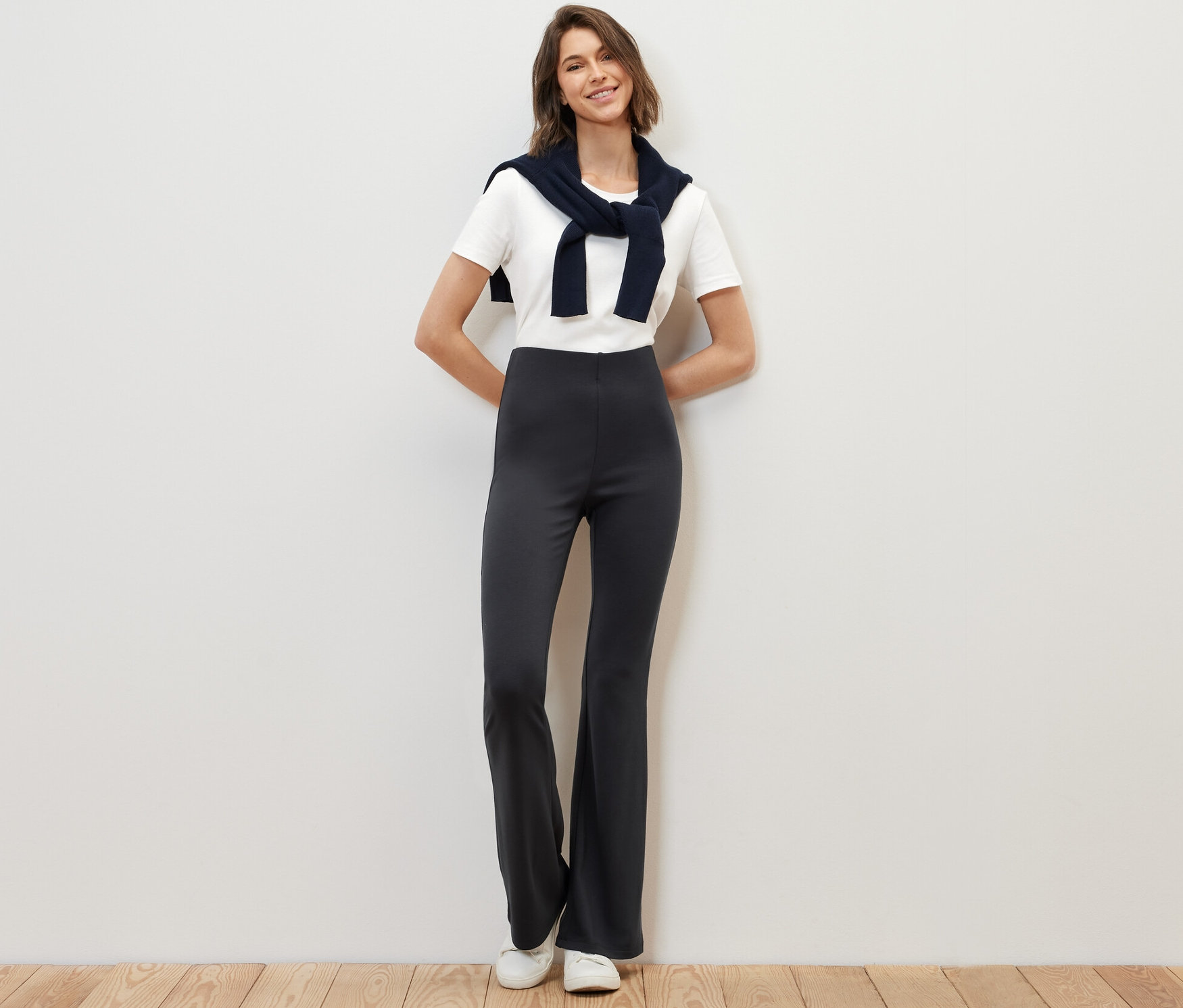 Egy nő áll és pózol sötétkék, bőszárú leggingben.