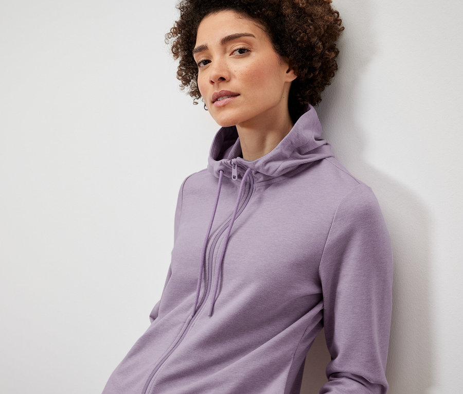 Nő lila szabadidőfelsőben pózol.