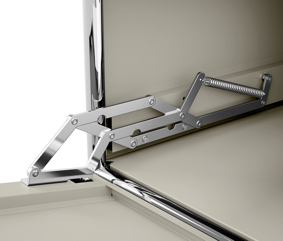 Közelkép egy krómozott zsanérműről rugóval, bézs szekrényajtón.