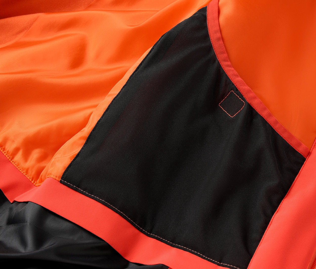 Egy narancssárga kabát részlete fekete zsebbel.