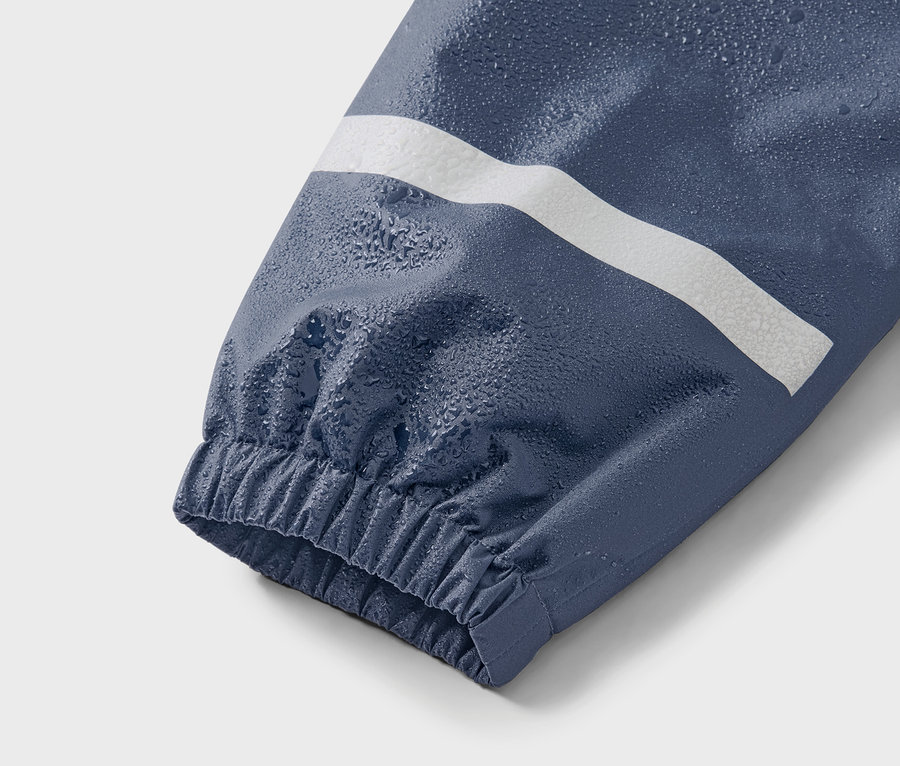 Egy kék kabátujja fehér csíkkal és vízcseppekkel.