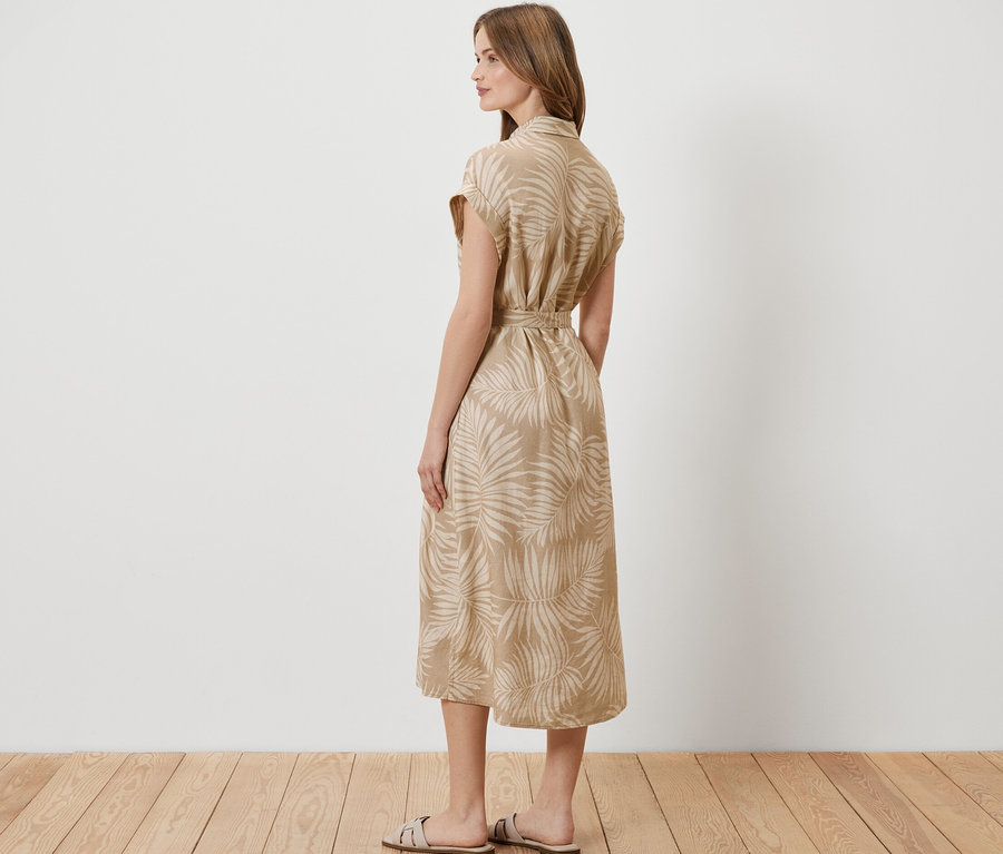 Nő áll oldalra, nyomott mintás lenvászon ruha van rajta.